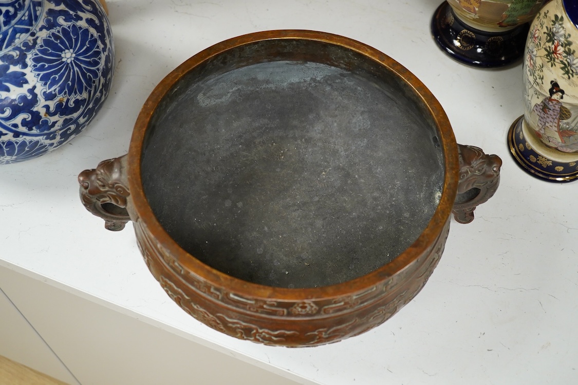 A large Chinese archaistic bronze censer, decorated in relief, with twin handles, 38cm in diameter
